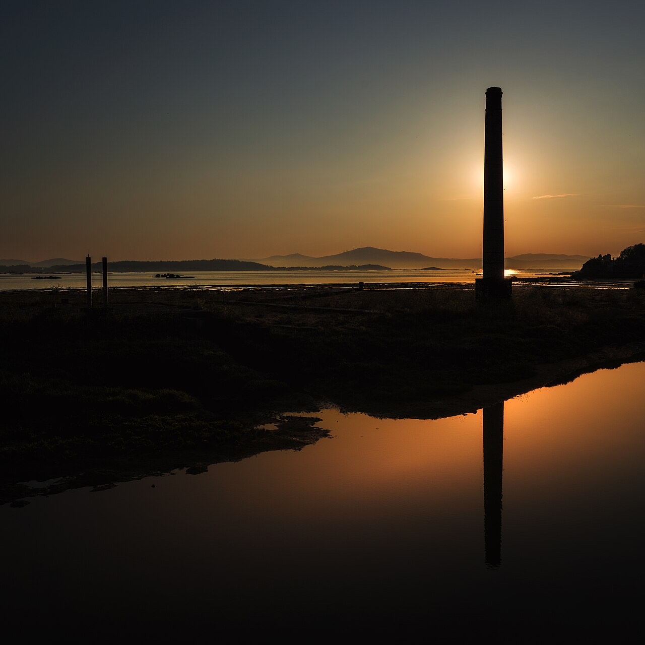 Solpor dourado sobre a ría de Arousa cunha antiga cheminea, en A Pobra do Caramiñal